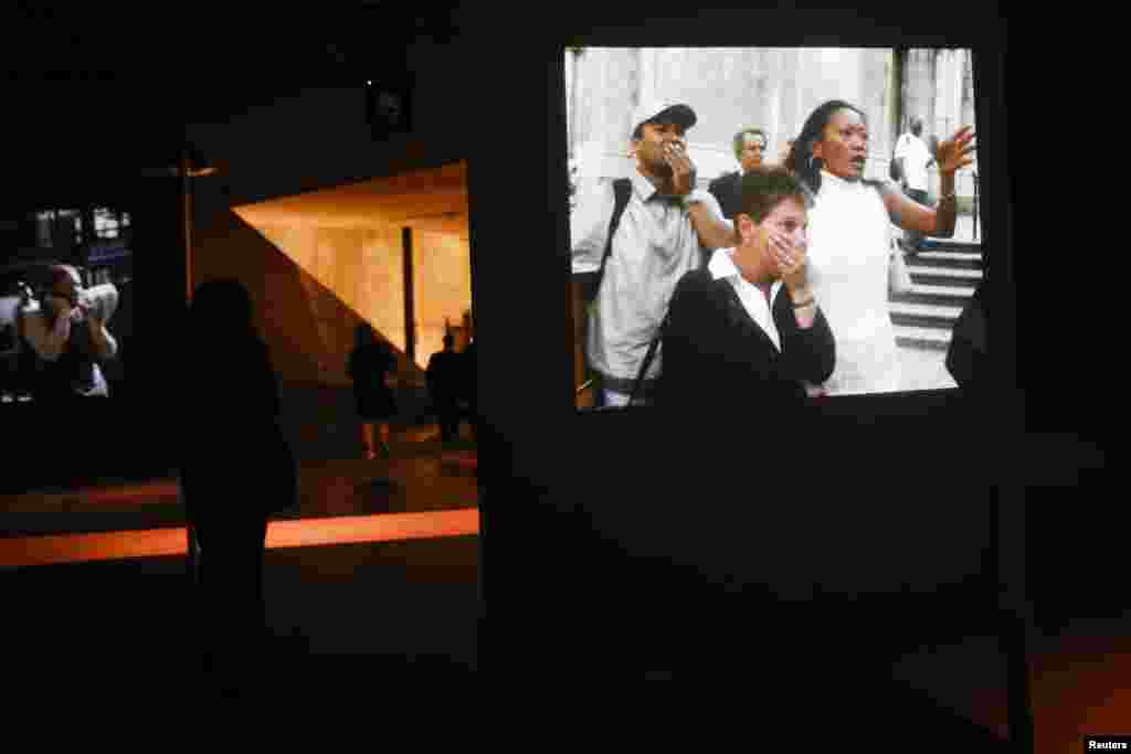 Visitors walk by projections of videos from September 11, 2001.