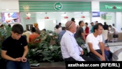 Turkmenistan. Dozens of people stand on queue to buy airplane tickets in Ashgabat.. men are sitting