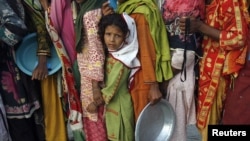 Flood victims stand in line to get food handouts while taking refuge with their family in a relief camp for flood victims in Sukkur, Sindh Province, on August 27.