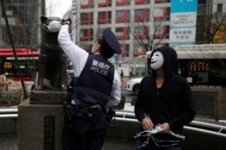 Полицейский символически надевает медицинскую маску на статую знаменитого японского пса Хатико, ставшего символом верности. Токио, 7 апреля 2020 года
