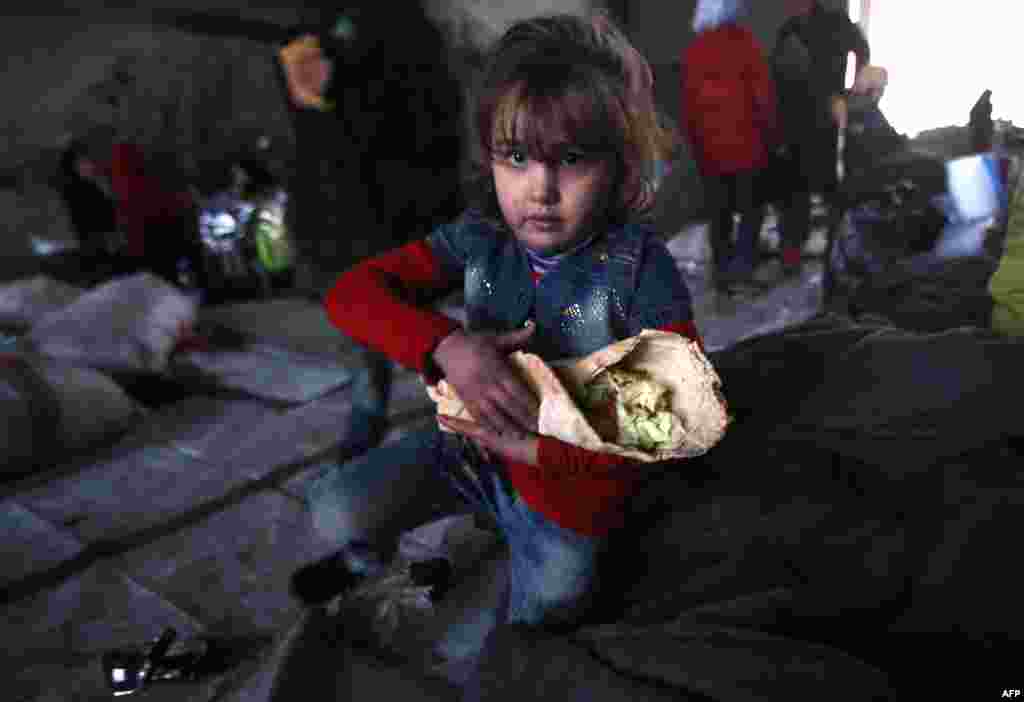 A Syrian girl who fled with her family from rebel-held areas of Aleppo carries food at a shelter in the Jibrin neighborhood. More than 50,000 Syrians have joined a growing exodus of terrified civilians from the besieged rebel-held east of Aleppo. (AFP/Youssef Karwashan)