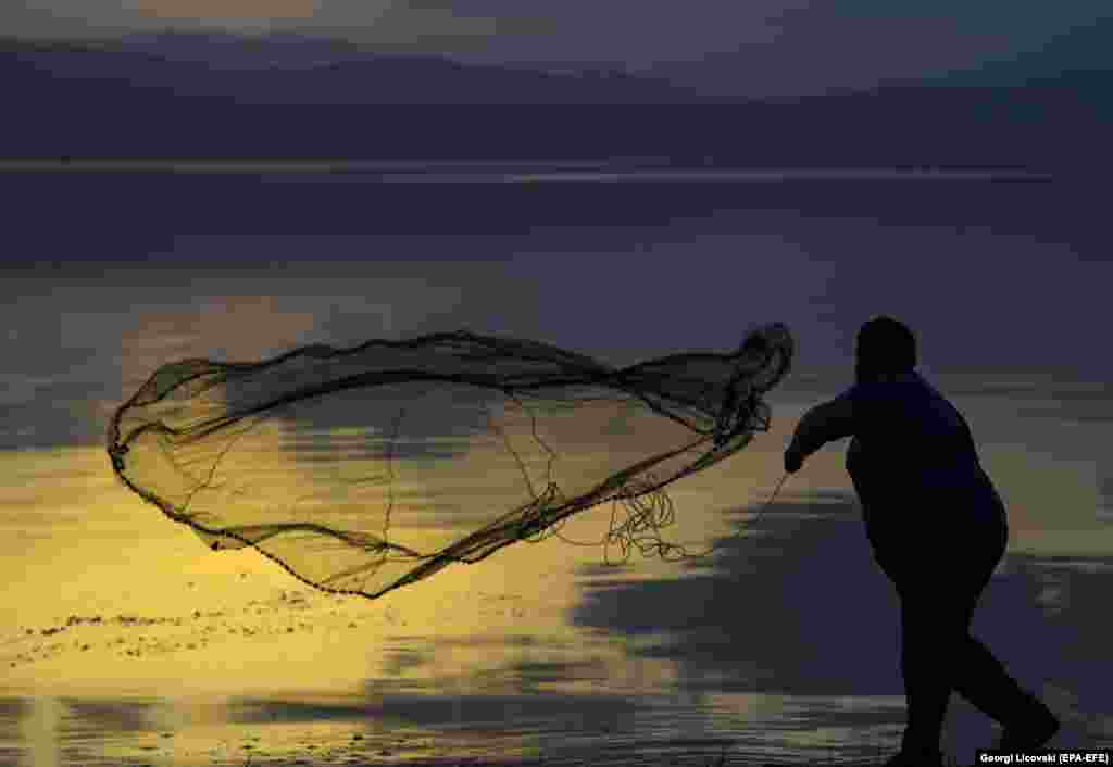 A man casts his fishing net at sunset on Lake Ohrid in Macedonia. (epa-EFE/Georgi Licovski)