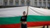 Девојка држи огромно бугарско знаме за време на протестот во септември 2020 година пред зградата на парламентот во Софија
