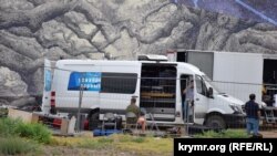 Обслуживающие фестиваль микроавтобусы, грузовики и фуры стоят на древней земле