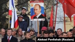 Russiýanyň prezidenti Wladimir Putiniň portretini göterip duran krymly ýaşaýjy.