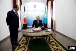 Франсуа Олланд смотрит, как Нурсултан Назарбаев подписывает документы на церемонии открытия института "Сорбонна - Казахстан"