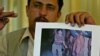 Saddam Saleh, a former prisoner at Abu Ghraib, shows a photograph at a 2004 press conference from the scandal that includes him in the middle of a group of naked prisoners being mocked by Lynndie England.