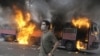 A supporter of defeated Iranian presidential candidate Mir Hossein Musavi stands in front of a burning bus during riots in Tehran.