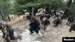 Afghan security forces and Afghan elders walk towards a check post in Parun, capital of Nuristan province on November 20.