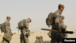 U.S. soldiers carry their luggage as they prepare to pull out of Iraq at Tallil Air Base near Nassiriya