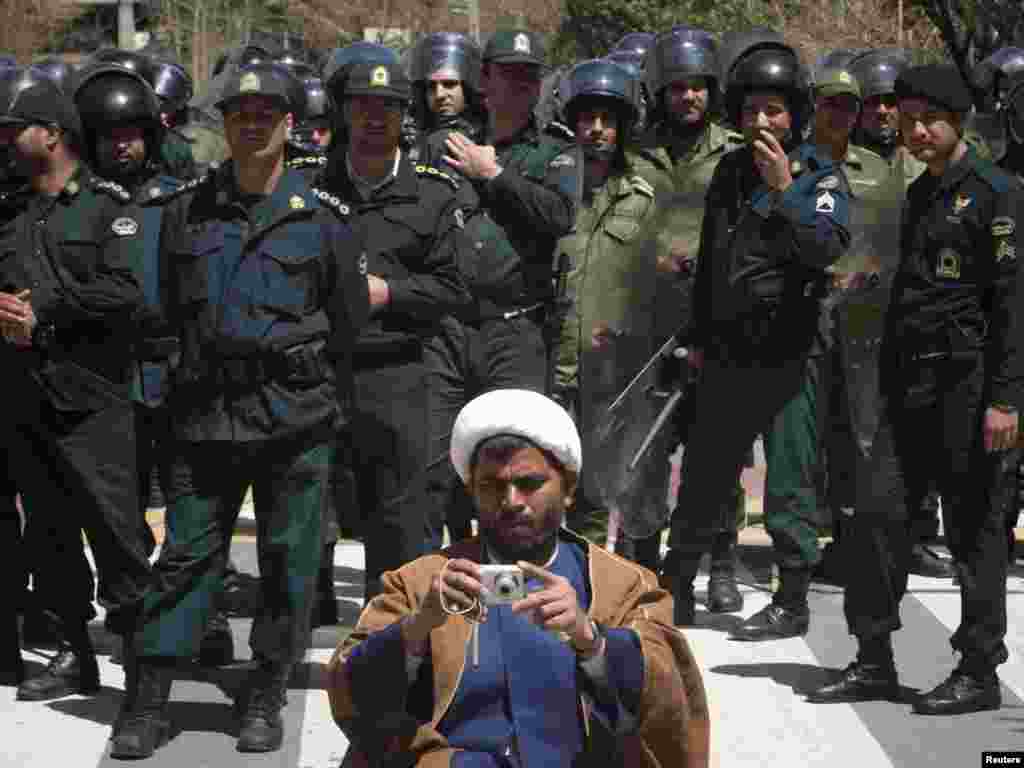 A foreign cleric living in Iran takes photographs as policemen stand guard outside of Saudi Arabia's embassy in Tehran on April 8. Clerics protested against Saudi Arabia's support of Bahrain in the suppression of Bahraini antigovernment protesters. Photo by Morteza Nikoubazl for Reuters
