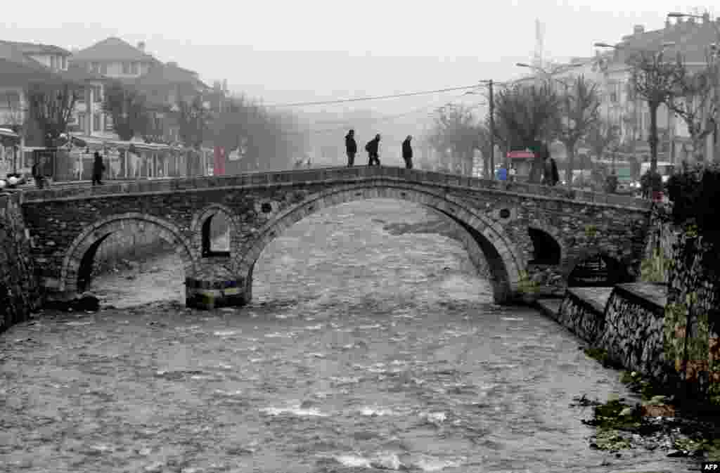 Pedestrians walk on the Old Stone Bridge during a cold and foggy morning in the town of Prizren, Kosovo. (AFP/Armend Nimani)