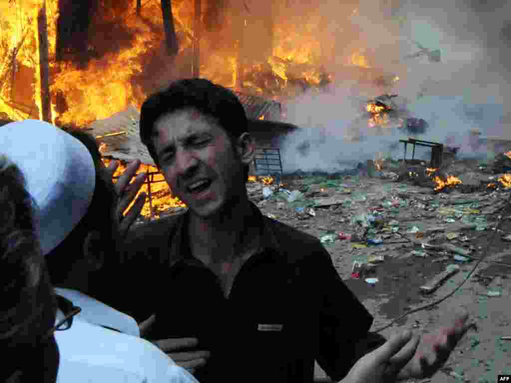 A Pakistani youth mourns as shops burn at a market following a deadly car bomb blast in Peshawar on October 28.