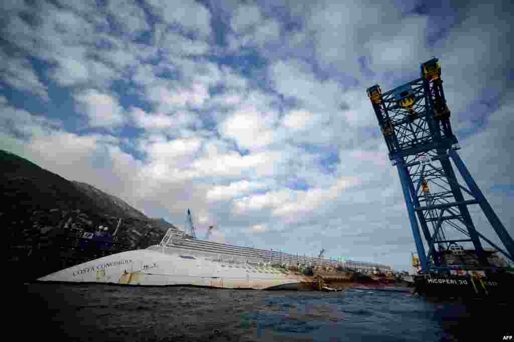 One year after a tragic accident that left 32 people dead, the &quot;Costa Concordia&quot; cruise ship still lies aground off the Italian island of Isola del Giglio. (AFP/Filippo Monteforte) 