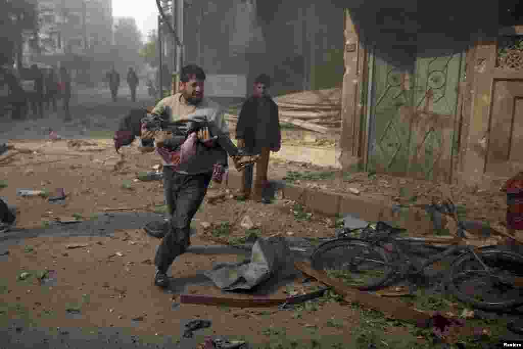 A man carries an injured girl from a site hit by what activists said were air strikes by forces loyal to Syria's President Bashar al-Assad, in the Douma neighborhood of Damascus on November 7.