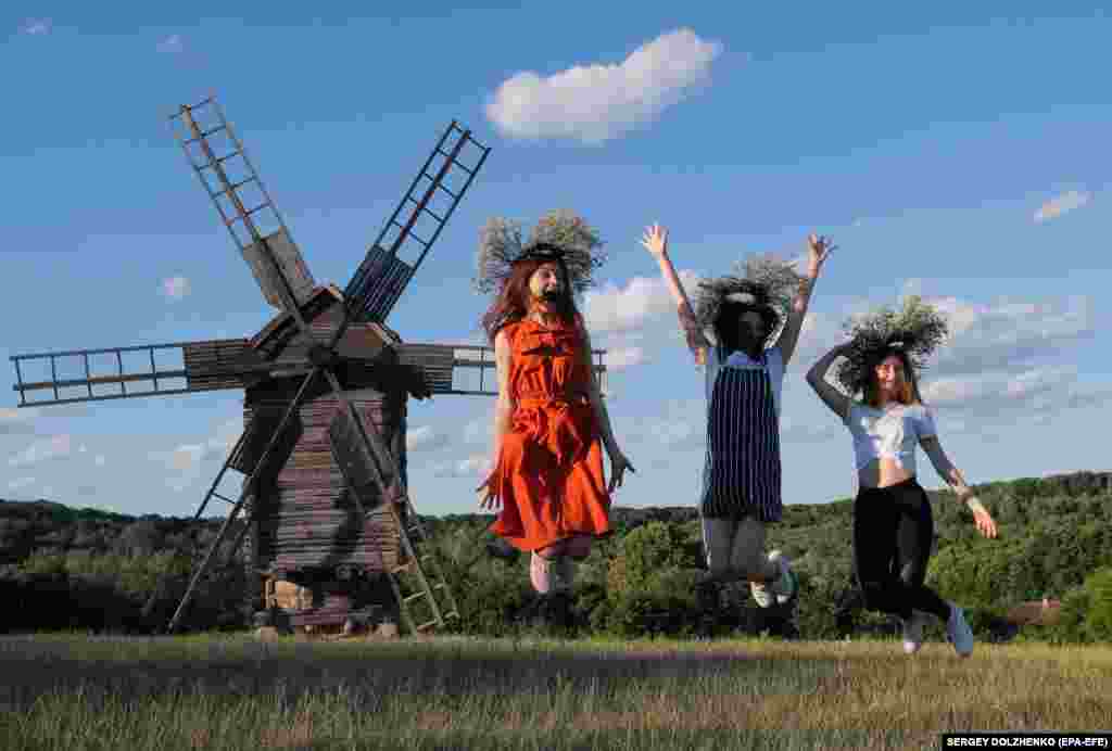 Ukrainian girls wearing floral headgear jump in front of an old windmill in Kyiv as they celebrate the traditional pagan holiday of Ivana Kupala. (epa-EFE/Sergey Dolzhenko)
