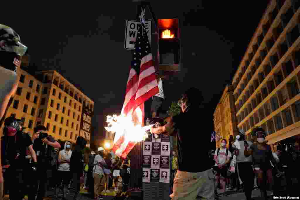 A demonstrator burns a U.S. flag during racial inequality protests near the White House in Washington, U.S., June 23, 2020. 