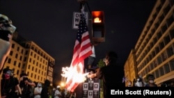 Протестующие жгут американский флаг во время протестов у Белого дома в Вашингтоне, 23 июня 2020 