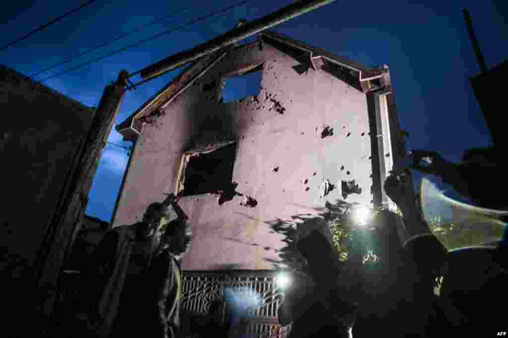 People stand near destroyed houses following clashes between Macedonian police and an armed group in Kumanovo.