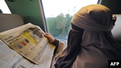 Ниқаб қиіп газет оқып отырған франциялық мұсылман әйел. 11 сәуір 2012 жыл