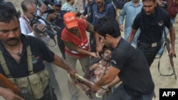 Pakistani police commandos carry the body of a suspected militant following a raid on a militant hideout in Lahore, July 17, 2014.