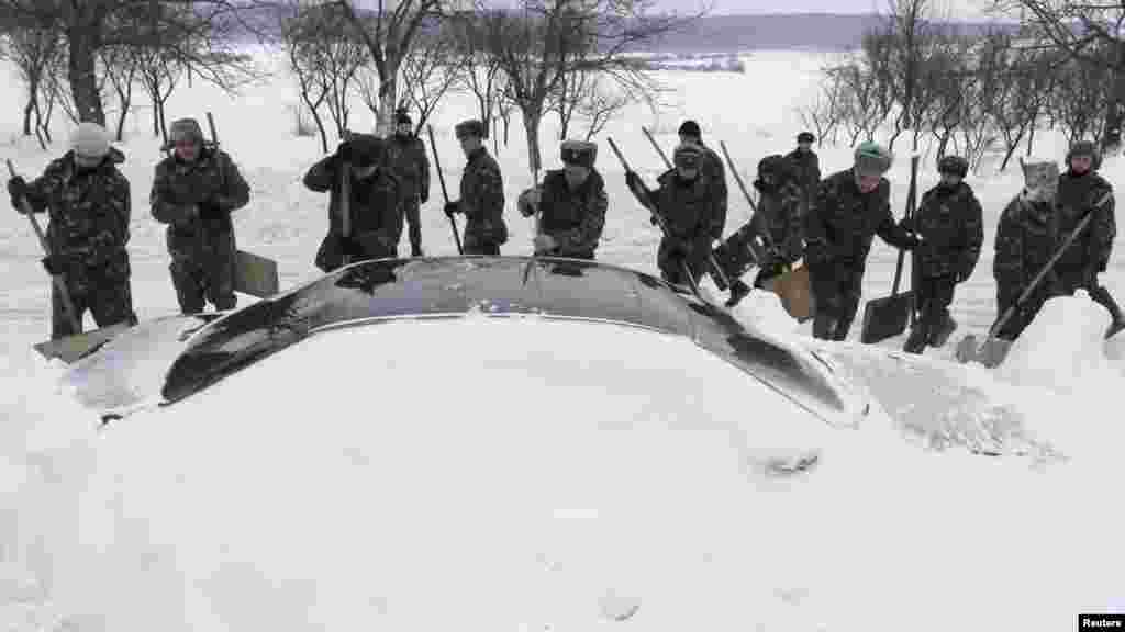 Emergency workers remove snow from around a car after a blizzard engulfed the western Ukrainian city of Brody, west of Kyiv, on December 17. Around 2,000 stranded vehicles were freed from the snow during the past 24 hours, according to the Emergency Ministry. (Reuters/Marian Striltsiv)