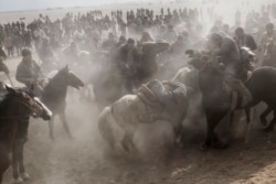 Horsemen rush for the headless goat during a game of buzkashi near Bukhara in 2014.