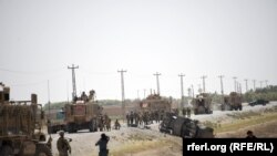 NATO soldiers keep watch near the wreckage of their vehicle at the site of a Taliban suicide attack in Kandahar on September 15.