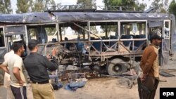 Pakistani security officials inspect the site of a suicide bomb blast that targeted a police bus in Karachi on February 13, 2014.