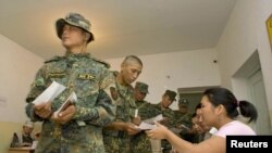 Soldiers receive ballot papers before casting their votes in a referendum at a polling station in Osh 