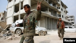 Syria -- A fighter of the Kurdish People's Protection Units (YPG) flashes a V-sign as he patrols in the streets in the northern Syrian town of Kobani, January 28, 2015