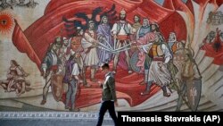 Një person kalon pranë një murali me motive etnike shqiptare në Shkup. Fotografi nga arkivi.