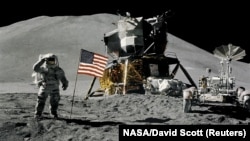 Astronaut James Irwin gives a military salute while standing beside the U.S. flag during Apollo 15 lunar surface extravehicular activity at the Hadley-Apennine landing site on the moon in August 1971.