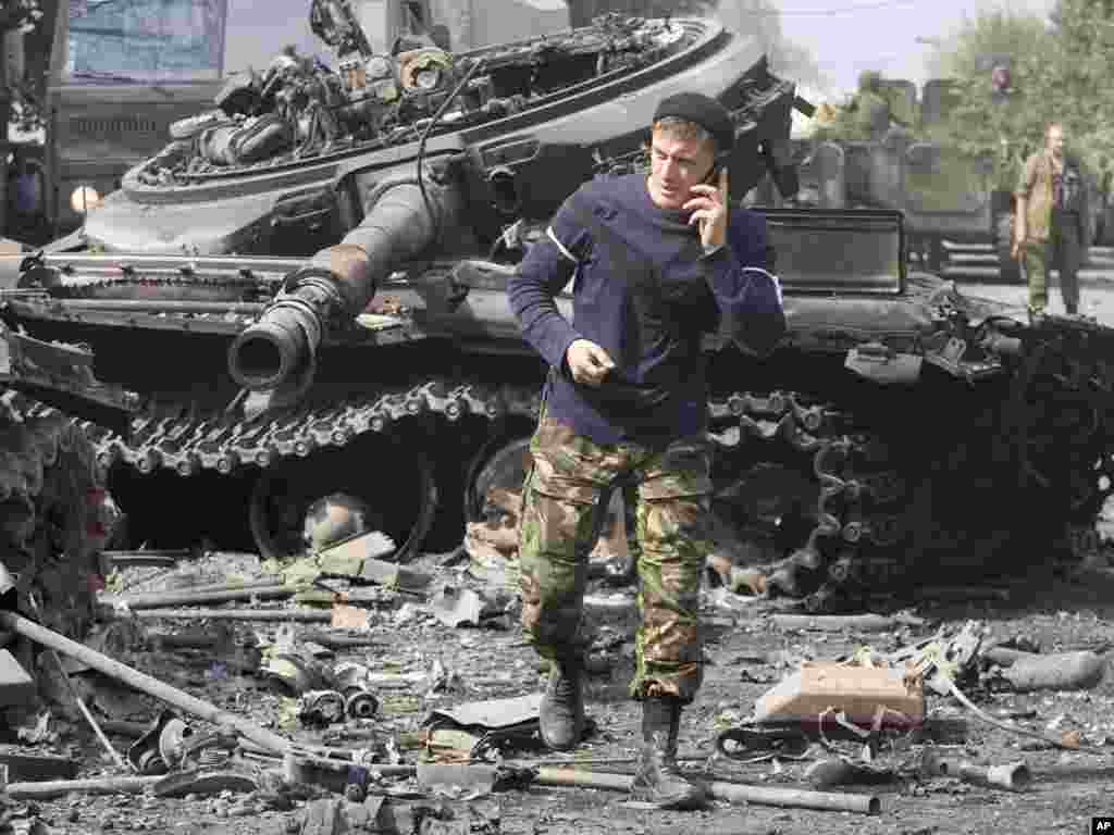 Осетинский солдат говорит по телефону около разрушенного танка в Цхинвали, 11 августа 2008 года