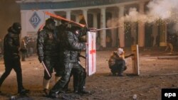 Protesters cover themselves behind selfmade shields as they launch a firework at riot police during a protest in downtown Kyiv on January 19.