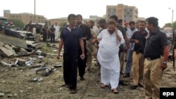 Senior police officer Aslam Chaudhry (in white), inspects the scene of a suicide car-bomb blast targeting his residence in Karachi in September 2011.