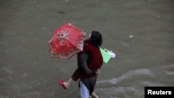 A man carries his daughter as he wades through a flooded road after heavy rains in Lahore, September 5, 2014.