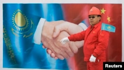 Сотрудник китайской нефтяной компании на фоне рекламного щита во время открытия трубопровода из Туркменистана в Китай. Жамбылская область, 2009 год.