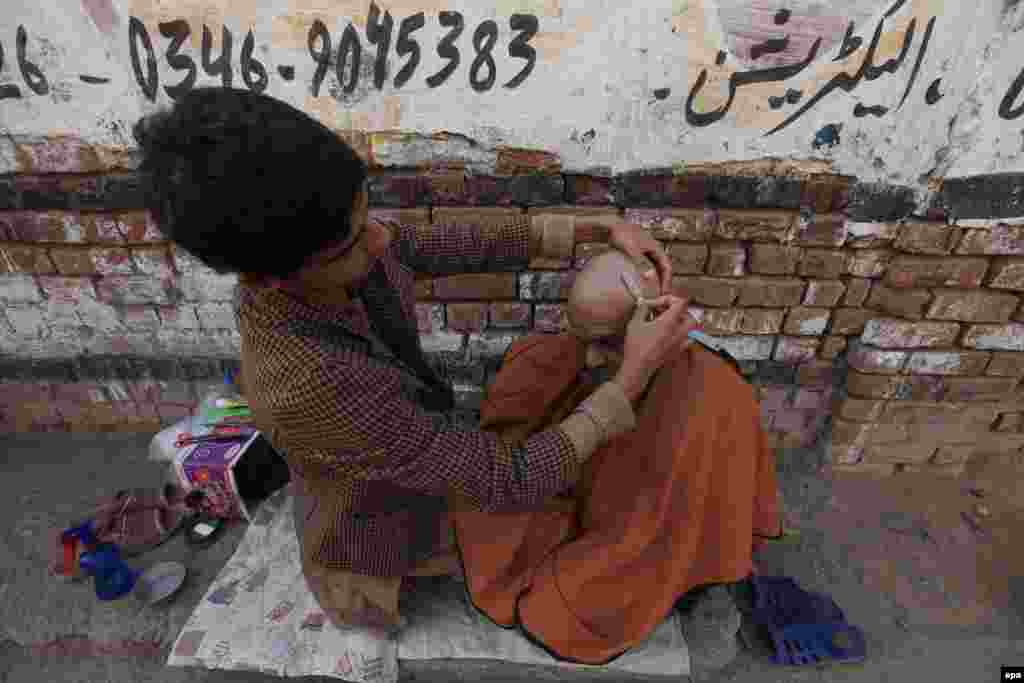 A Pakistani barber shaves a customer's head at a roadside shop in Peshawar. (epa/Bilawal Arbab)