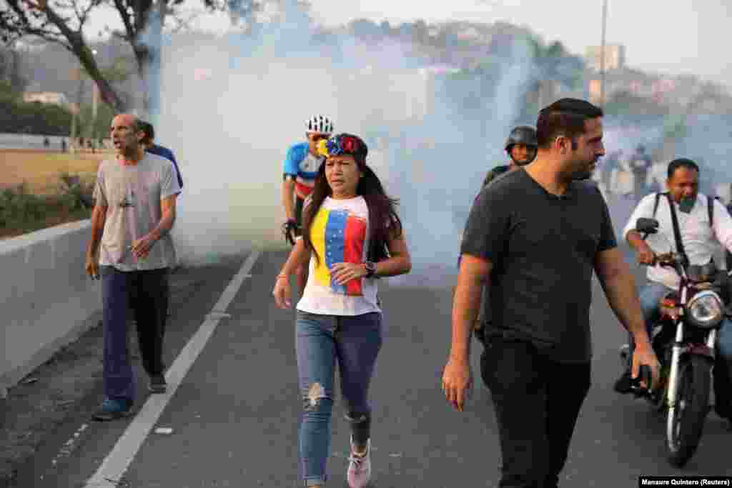 People run away from tear gas near the Generalisimo Francisco de Miranda Air Base.&nbsp;