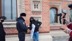 Полицейский спрашивает документы у участника акции у посольства Франции в Москве, 29 октября 2020