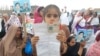 FILE: Thousands of women, children, and men held up photos, placards, or the national ID cards of their missing family members in Peshawar, Pakistan in April 2018.