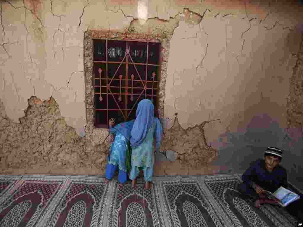 Pakistani girls peek in on other children attending a daily Islamic religious class in a mosque in a slum area on the outskirts of Islamabad, Pakistan, on May 10. Photo by Muhammed Muheisen for AP