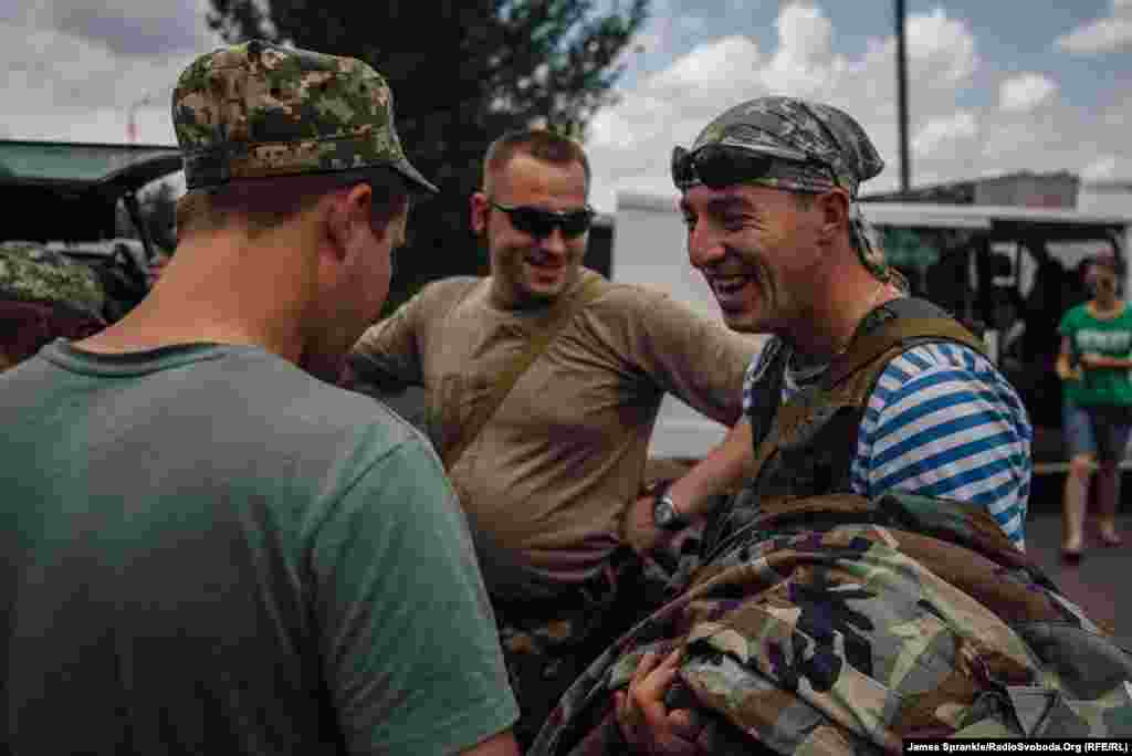 Soldiers from a civil-military cooperation unit (CIMIC) joke with soldiers of the 17th Battalion as they pick up donated uniforms.