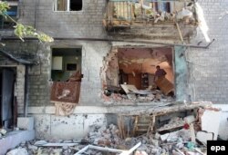 Un om își curăță casa distrusă de lupte în Horlivka.