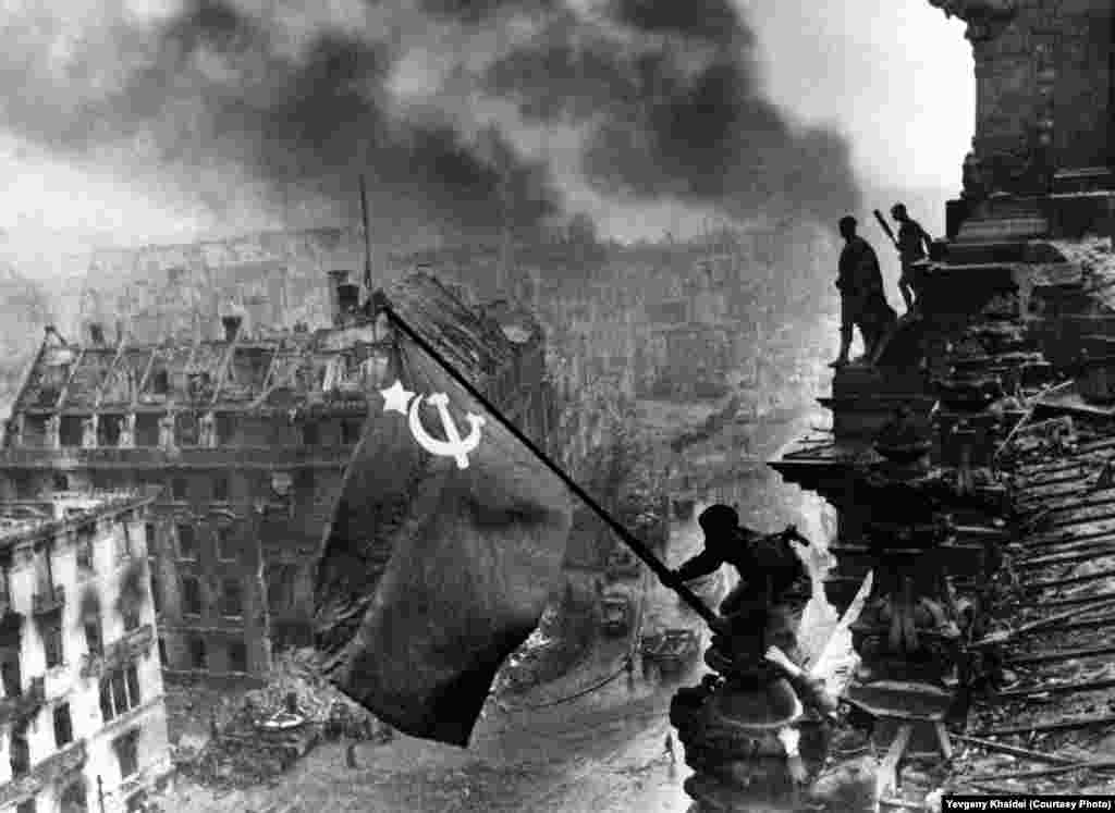Soviet flag flies above the Reichstag building as Berlin smolders, May 2, 1945