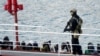 Мальтийский полицейский охраняет арестованных мигрантов в порту Валетты. 28 марта 2019 года