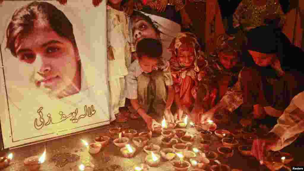 OCTOBER 12, 2012 -- Children light oil lamps at a Peshawar school beside a picture of 14-year-old Malala Yousafzai, who was gunned down three days earlier by Taliban attackers for speaking out against militants and promoting education for girls. (REUTERS/Athar Hussain)