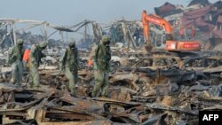 Тяньцзиндегі жарылыс орнын тазалап жүрген жұмысшылар. Қытай, 20 тамыз 2015 жыл.