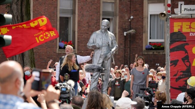 MLPD leader Gabi Fechtner (right, in gray) sings the Internationale next to the Lenin monument.